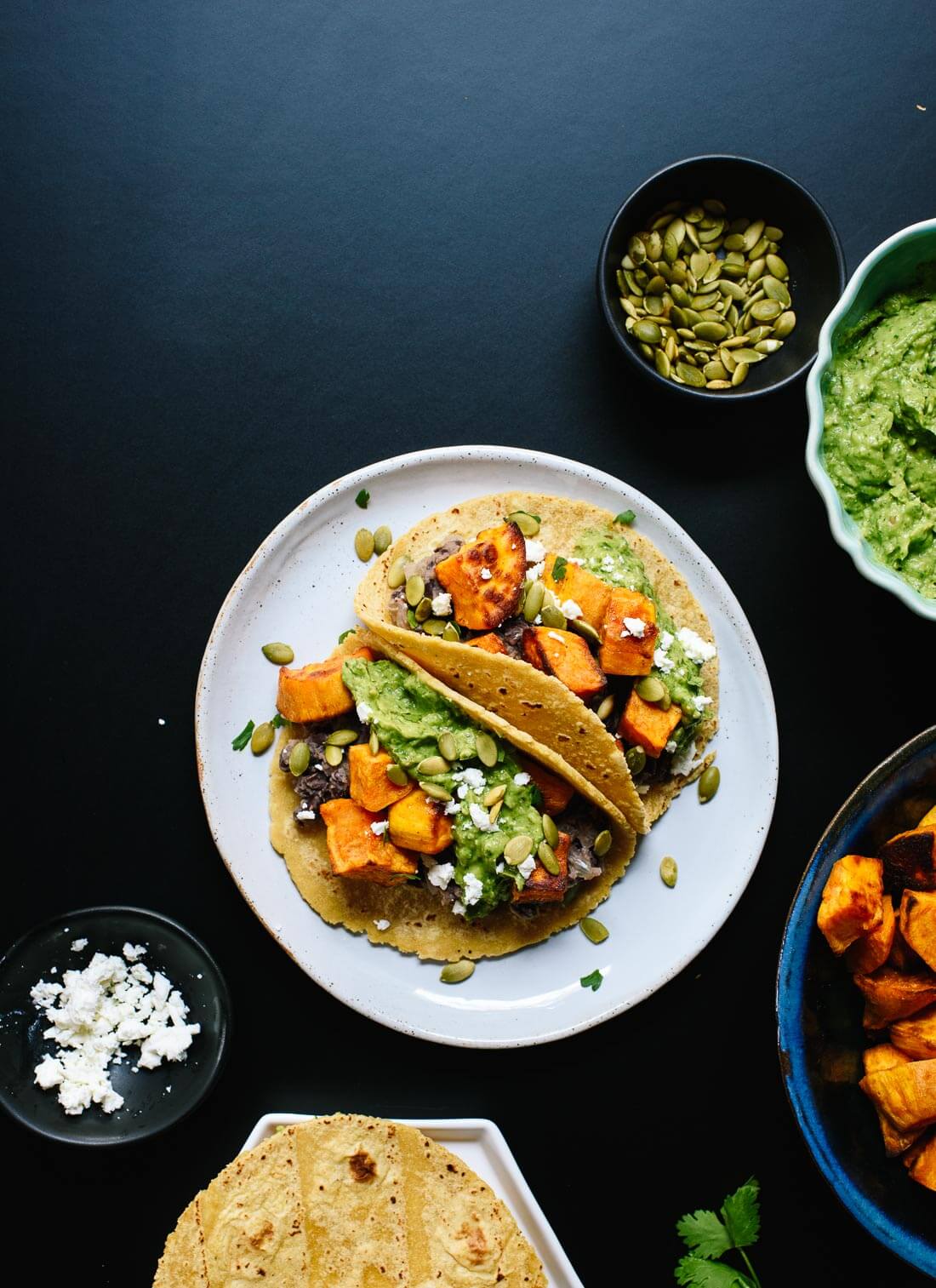 Delicious black bean and sweet potato tacos with avocado sauce and feta on top! Everyone loves these vegetarian tacos. cookieandkate.com