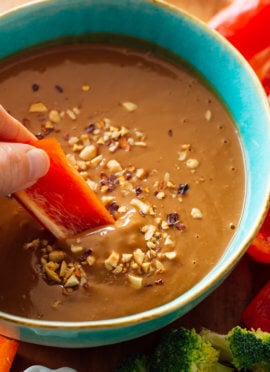 dipping slice of bell pepper into peanut sauce