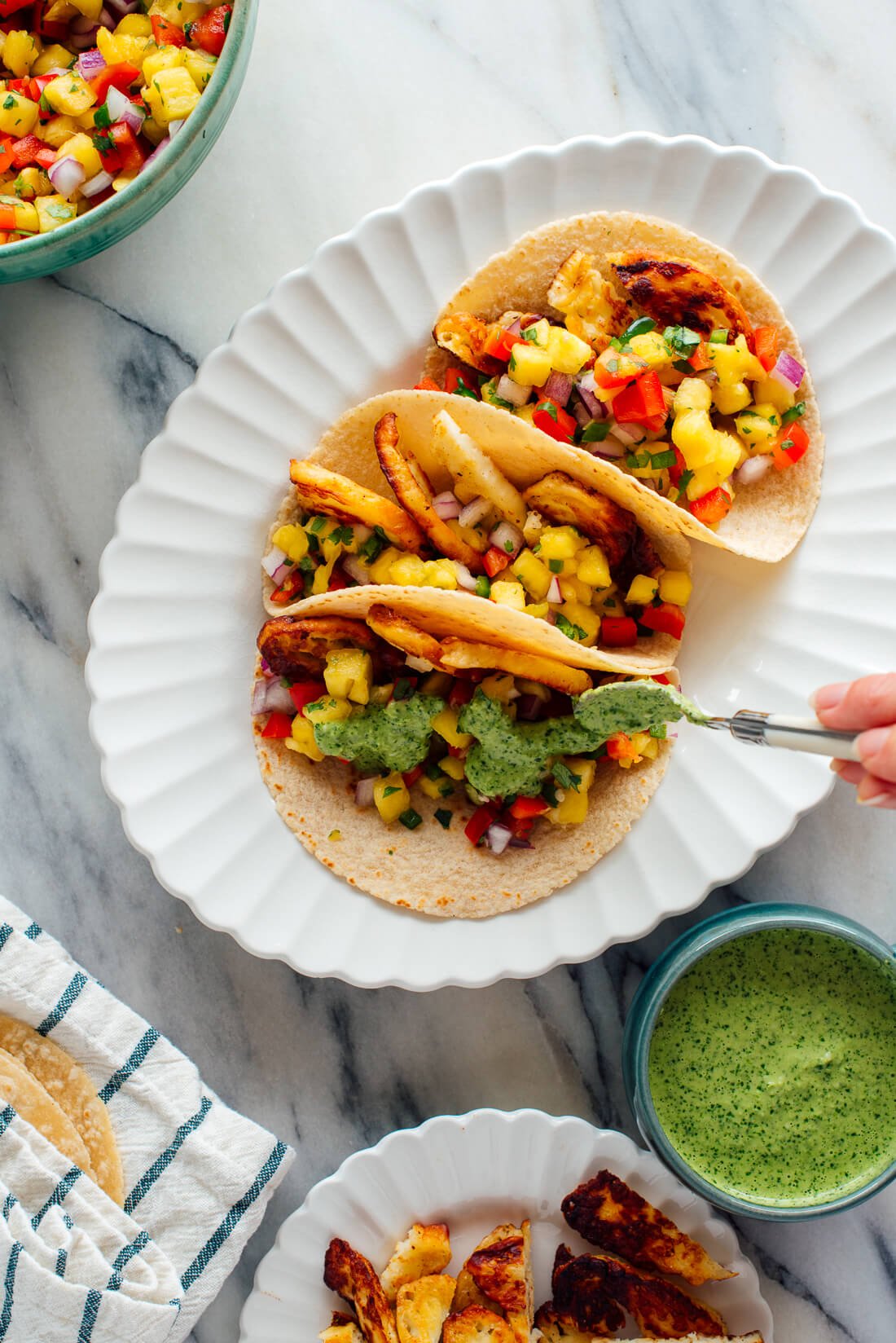 drizzling aji verde onto pineapple halloumi tacos