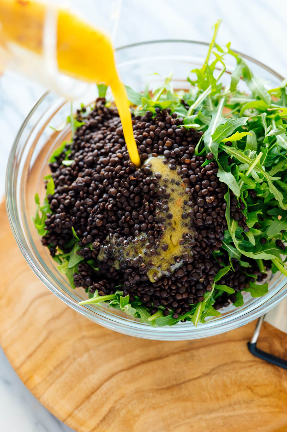 drizzling lemon dressing over salad