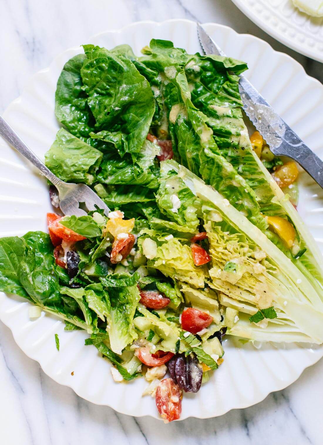 Greek salad recipe, with a base of halved romaine lettuce. cookieandkate.com