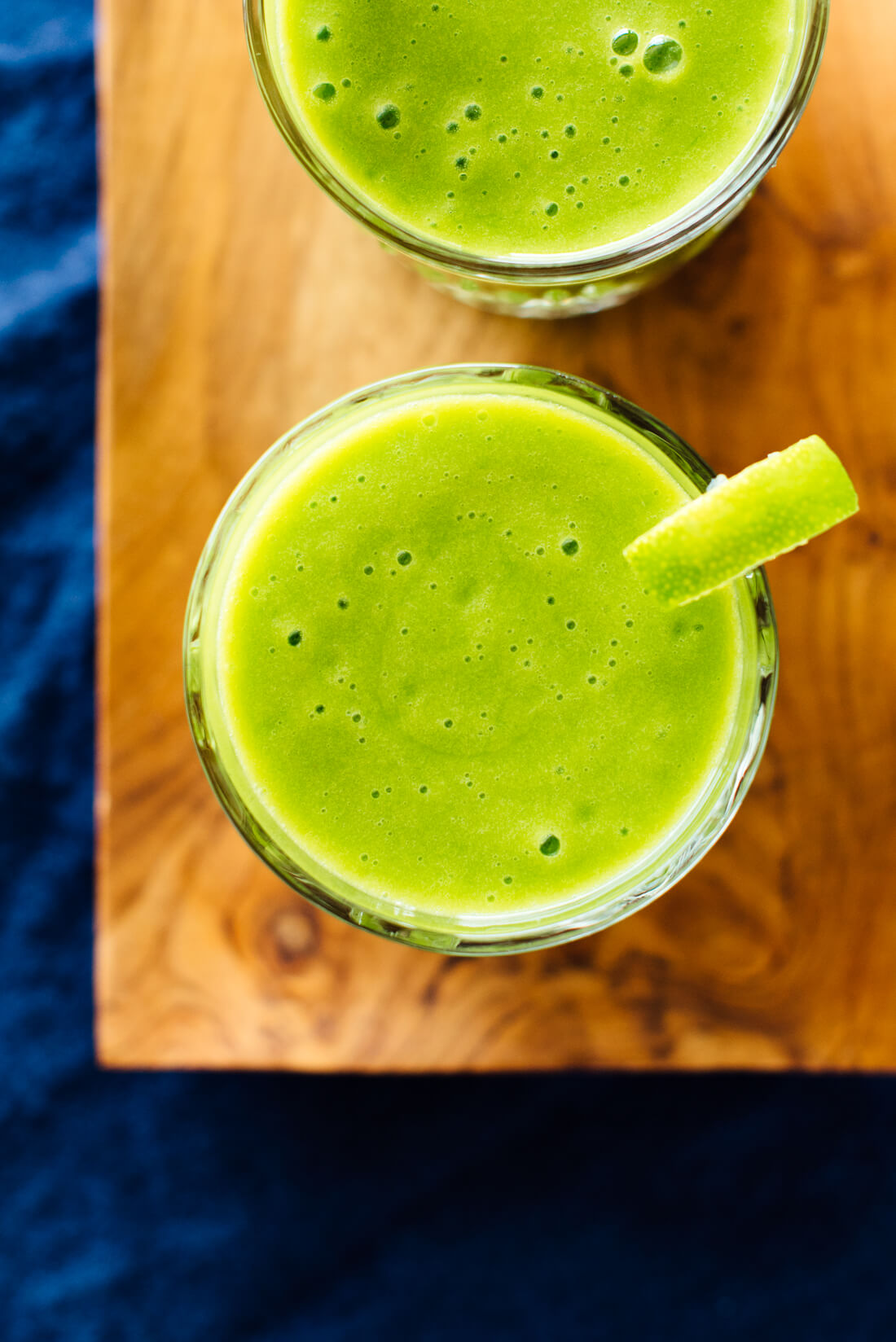 This refreshing green smoothie recipe features frozen mango and pineapple, fresh orange, lime and spinach! You can't taste the spinach but it adds an extra boost of nutrients. cookieandkate.com