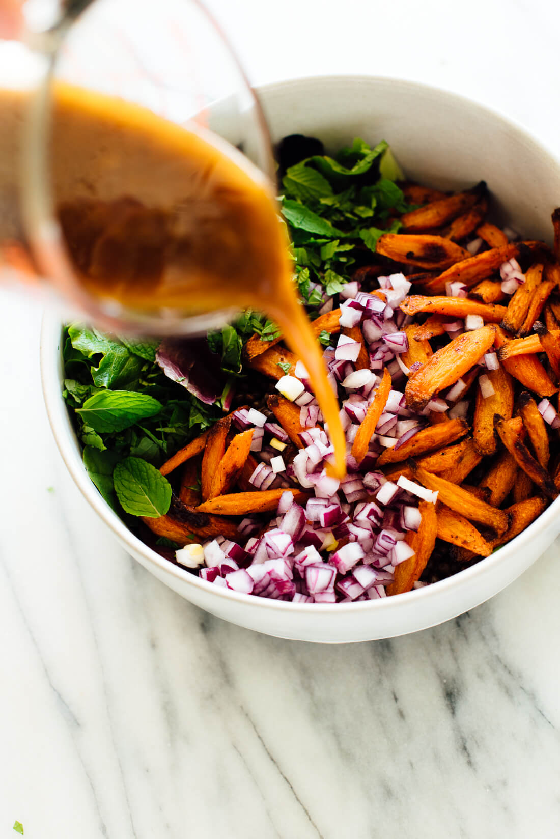 pouring salad dressing onto masala lentil salad