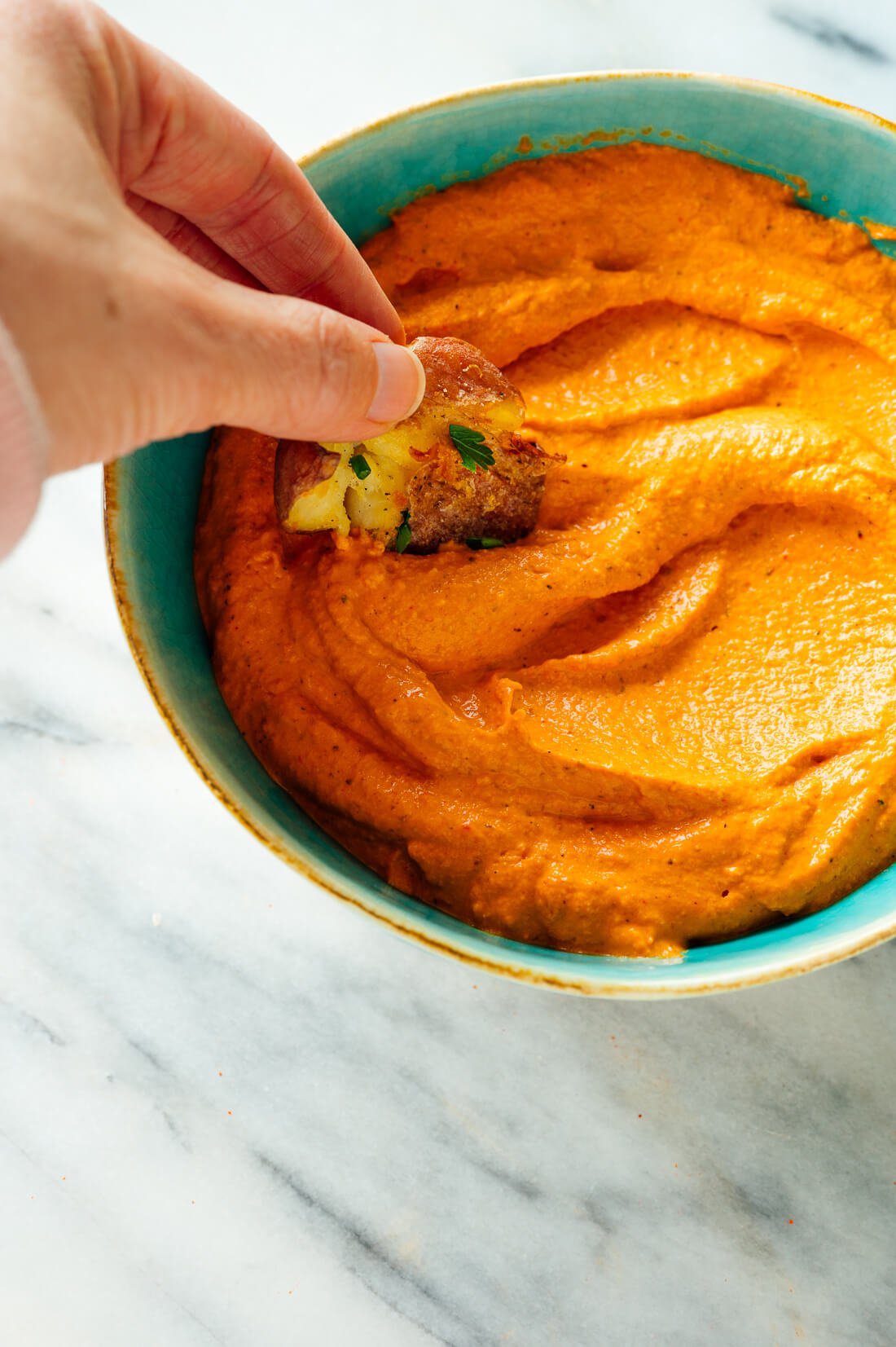 smashed potato dipping into romesco sauce