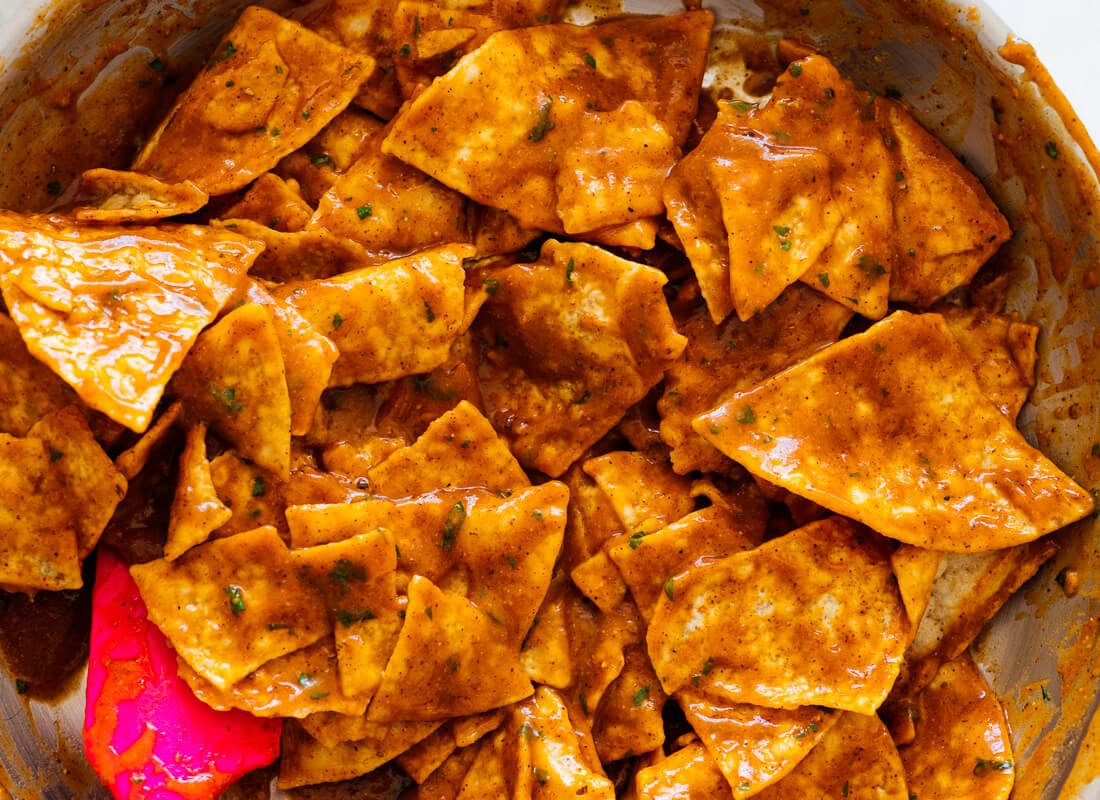 tortilla chips tossed in red enchilada sauce